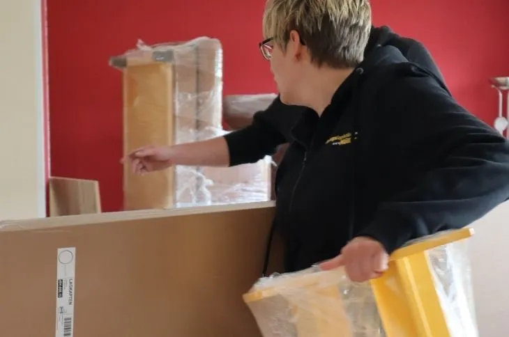 umzugshelferin verpackt moebel mit schutzfolie und karton